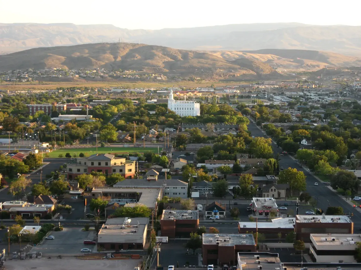 St. George, Utah: the city spread across a desert valley, with red sandstone bluffs and dark lava-rock ridges behind it.